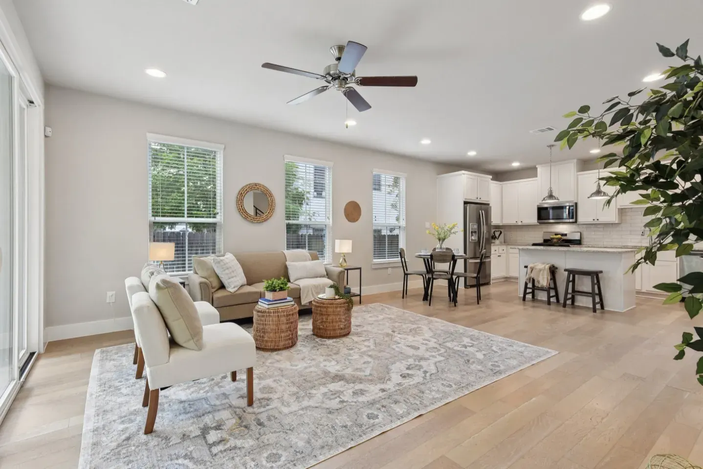Open living and kitchen area staged with neutral chairs and rug