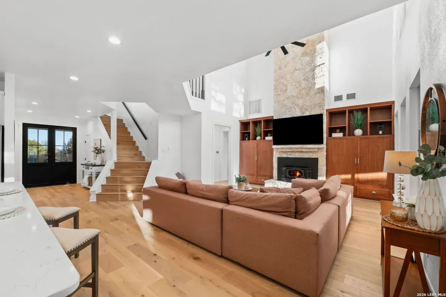 Vaulted living room staged near staircase and fireplace